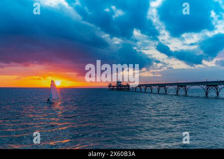 Clevedon Pier bei Sonnenuntergang mit einem farbenfrohen Horizont und einem Streifen Sonnenlicht, der über das Meer geht Stockfoto