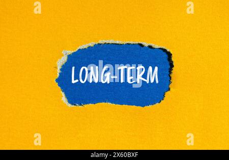 Langzeit-Wörter auf gerissenem gelbem Papier mit blauem Hintergrund. Konzeptionelles langfristiges Symbol. Kopierbereich. Stockfoto