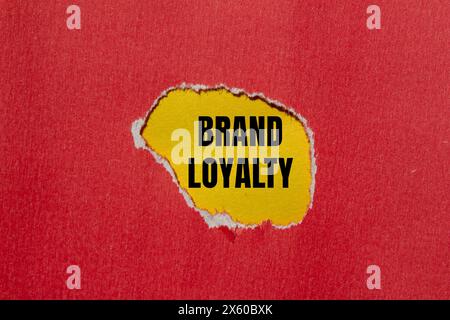 Markenbegriffe auf gerissenem rotem Papier mit gelbem Hintergrund. Konzeptionelles Symbol für Markenloyalität. Kopierbereich. Stockfoto