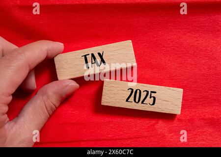Steuer 2025 Wörter auf Holzblöcken mit rotem Hintergrund. Symbol für die konzeptionelle Steuer 2025. Kopierbereich. Stockfoto