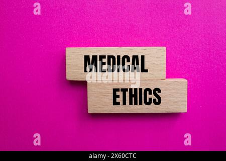 Medizinische Ethik Wörter auf Holzblöcken mit rosa Hintergrund geschrieben. Konzeptuelles medizinisches Ethiksymbol. Kopierbereich. Stockfoto