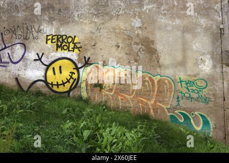 Ferrol Molar Street Art, gesprüht auf eine schroffe Wand eines alten Gebäudes mit einer grasbewachsenen Bank in den engen Seitenstraßen von Ferrol, Nordspanien 2024. Stockfoto