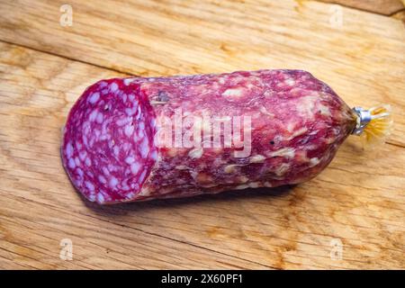 Ein großes Stück geräucherte Wurst auf einem hölzernen Schneidebrett, Nahaufnahme. Das Bild kann verwendet werden, um die Qualität der Zutaten in lebensmittelbezogenen Artikeln darzustellen. Stockfoto