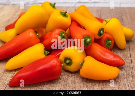 Köstliche und gesunde rote, orange und gelbe süße Paprika auf einem hölzernen Kochbrett, bereit für die Zubereitung in einem Rezept Stockfoto