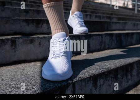 Männliche Beine in weißen Sneakers. Ein Spaziergang durch die Stadt. Fitness im Freien Stockfoto