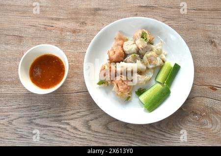 Gedünsteter Fisch und Garnelenknödel garnieren knusprig gebratenen Knoblauch mit Gurke auf Teller, mit würziger und saurer Sauce Stockfoto