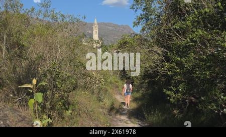 Wanderer auf dem Trail zu einem hoch aufragenden Kirchturm Stockfoto