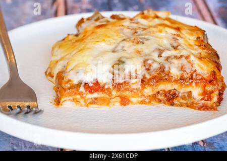 Frisch zubereitete und gebackene hausgemachte Rindfleischlasagne. Eine einzelne Portion wird auf einem Teller serviert und besteht aus mehreren Schichten Nudelblätter, die mit einer Ragu-Sauce gefüllt sind Stockfoto