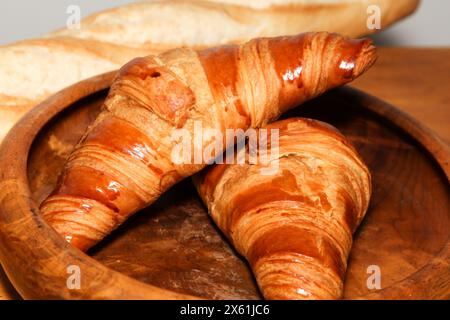 Zwei glasierte, frisch gebackene französische Croissants in einer Holzschale, die als Teil eines kontinentalen Frühstücks in Frankreich serviert werden. Stockfoto