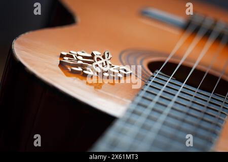 Ein Haufen hölzerner Musiknoten auf dem Soundboard einer klassischen Gitarre, Nahaufnahme. Das Konzept des Komponierens und Aufführens von Musik Stockfoto