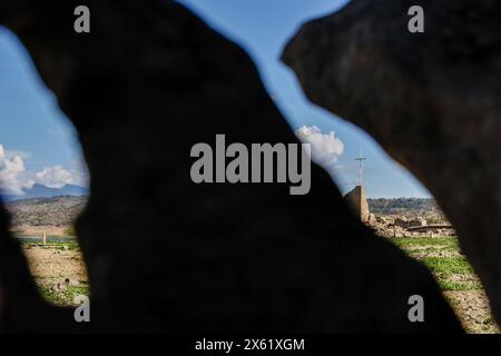 Pantabangan, Philippinen. 12. Mai 2024, Pantabangan, Pantabangan, Philippinen: Reste der alten versunkenen Stadt Pantabangan, die wieder aufgetaucht sind, werden durch einen verwelkten Baum an einem Stausee gesehen, als Folge einer schweren Dürre aufgrund der steigenden Temperaturen auf den Philippinen. Quelle: ZUMA Press, Inc./Alamy Live News Stockfoto