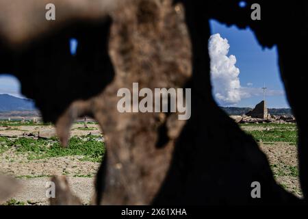 Pantabangan, Philippinen. 12. Mai 2024, Pantabangan, Pantabangan, Philippinen: Reste der alten versunkenen Stadt Pantabangan, die wieder aufgetaucht sind, werden durch einen verwelkten Baum an einem Stausee gesehen, als Folge einer schweren Dürre aufgrund der steigenden Temperaturen auf den Philippinen. Quelle: ZUMA Press, Inc./Alamy Live News Stockfoto