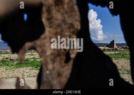 Pantabangan, Philippinen. 12. Mai 2024, Pantabangan, Pantabangan, Philippinen: Reste der alten versunkenen Stadt Pantabangan, die wieder aufgetaucht sind, werden durch einen verwelkten Baum an einem Stausee gesehen, als Folge einer schweren Dürre aufgrund der steigenden Temperaturen auf den Philippinen. Quelle: ZUMA Press, Inc./Alamy Live News Stockfoto
