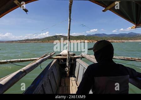Pantabangan, Philippinen. 12. Mai 2024, Pantabangan, Pantabangan, Philippinen: Ein Seemann auf einem Boot, der auf die Überreste der alten versunkenen Stadt Pantabangan zusteuert, die infolge einer schweren Dürre aufgrund der steigenden Temperaturen auf den Philippinen an einem Stausee wieder aufgetaucht sind. Quelle: ZUMA Press, Inc./Alamy Live News Stockfoto