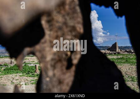 Pantabangan, Philippinen. 12. Mai 2024, Pantabangan, Pantabangan, Philippinen: Reste der alten versunkenen Stadt Pantabangan, die wieder aufgetaucht sind, werden durch einen verwelkten Baum an einem Stausee gesehen, als Folge einer schweren Dürre aufgrund der steigenden Temperaturen auf den Philippinen. Quelle: ZUMA Press, Inc./Alamy Live News Stockfoto