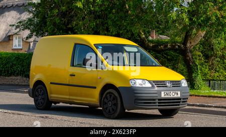 Stoke Goldington, Großbritannien - 12. Mai 2024:2010 gelber Volkswagen Caddy-Van, der durch ein englisches Dorf fährt Stockfoto