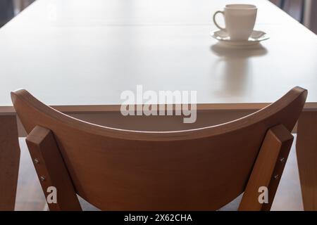 Möbel. Küche Holzstuhl Nahaufnahme auf verschwommenem Hintergrund des Küchentischs mit weißer Tasse Stockfoto