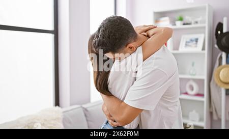 Ein liebevolles Paar umarmt sich herzlich in einem gemütlichen, gut beleuchteten Wohnzimmer und drückt Zuneigung und Zweisamkeit aus. Stockfoto