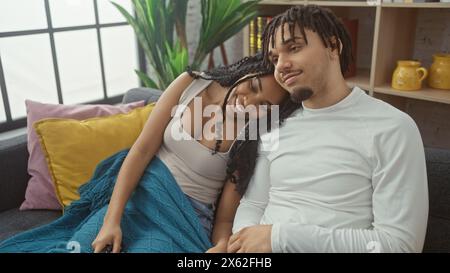 Ein liebevolles Paar kuschelt sich bequem auf einem Sofa in einem gemütlichen Wohnzimmer, was eine warme Beziehung in einem Innenbereich veranschaulicht. Stockfoto