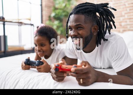 Vater und Tochter spielen Videospiel und liegen im Bett im Schlafzimmer Stockfoto