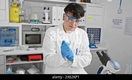 Ein junger Mann in einem Labormantel führt ein wissenschaftliches Experiment drinnen durch, das Professionalität und Konzentration ausstrahlt. Stockfoto