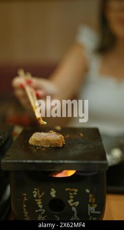 Köstliches Abendessen, eine junge Frau genießt traditionelle japanische Gyukatsu in einem modernen Restaurant, eine Mahlzeit aus einem Teller mit geröstetem Rindfleisch, mit ihrer praktischen Hilfe Stockfoto