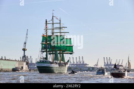 Hamburg, Deutschland. Mai 2024. Das Jugendsegel-Ausbildungsschiff Alexander von Humboldt II und andere Schiffe segeln während der Abfahrtsparade zum 835. Hamburger Hafengeburtstag auf der Elbe im Hafen. Container-Portalkrane sind im Hintergrund zu sehen. Die Hamburger sehen den 7. Mai 1189 als Geburtsdatum ihres Hafens an – damals erhielten die Bürger für ihre Schiffe auf der Elbe zollfreie Fahrten von der Stadt in die Nordsee. Quelle: Georg Wendt/dpa/Alamy Live News Stockfoto