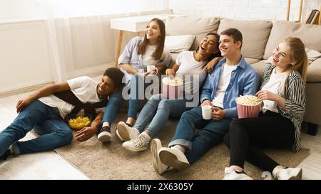 Eine Gruppe Teenager sitzt auf dem Boden und isst Popcorn Stockfoto