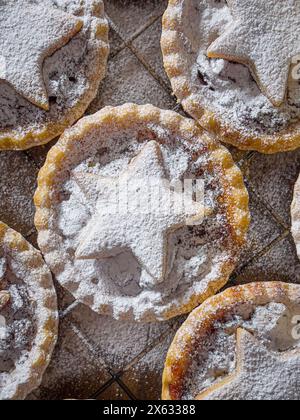 Frisch gebackene, mit Sternchen überzogene Hackpasteten, in Puderzucker bestäubt und auf einer Drahtschale gekühlt. Stockfoto