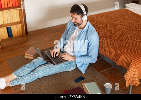 Mann sitzt auf dem Boden mit Laptop, Hochwinkelansicht Stockfoto