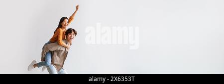 Hübscher junger asiatischer Mann, der seiner Freundin Huckepack mitreitet Stockfoto