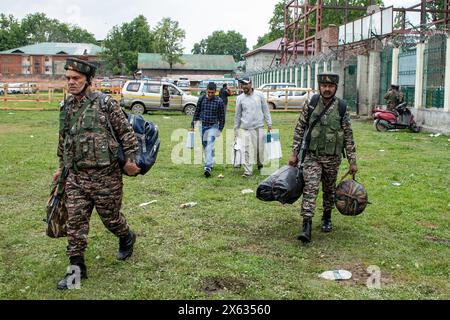 Srinagar, Jammu Und Kaschmir, Indien. Mai 2024. Indische paramilitärische Truppen gehen, während Wahloffiziere elektronische Wahlgeräte (EVM) und Voter Verifiable Paper Audit Trail (VVPAT) zu einem Bus transportieren, der vor der vierten Wahlphase der indischen Parlamentswahlen in Srinagar zu den Wahllokalen transportiert wird. (Credit Image: © Faisal Bashir/SOPA Images via ZUMA Press Wire) NUR REDAKTIONELLE VERWENDUNG! Nicht für kommerzielle ZWECKE! Stockfoto