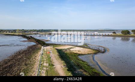 Überreste einer alten Eisenbahnbrücke zwischen Langstone (oben im Bild) und Hayling Island in Hampshire, Großbritannien, mit Straßenbrücke dahinter Stockfoto