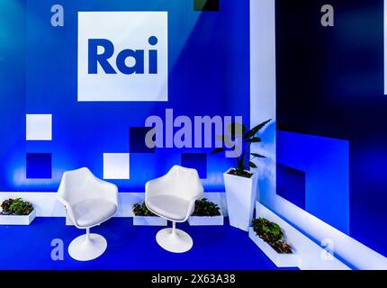 Turin, Italien - 10. Mai 2024: RAI Radio Televisione Italiana Logo auf blauer Wand mit blau-weißen Bildern im Eckraum mit weißen Interviewstühlen. Stockfoto