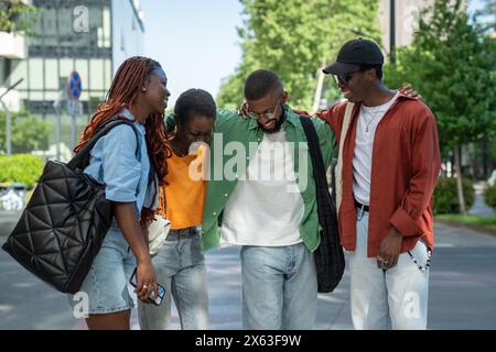 Fröhliche Gruppe schwarzer Studenten spaziert durch die Innenstadt, umarmt sich zusammen lachend, plaudernd, viel Spaß, viel Spaß. Stockfoto