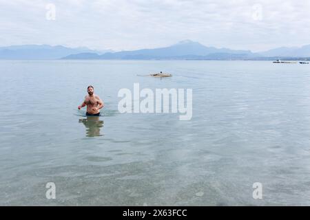 Weitwinkelansicht eines Mannes mittleren Alters, der aus dem Wasser des Sees mit Bergen am Horizont kommt Stockfoto