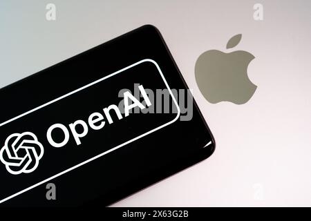 Apple-Laptop mit Smartphone oben mit OpenAI-Logo. Konzept für fortschrittliche Technologie und KI-Führung. Stafford, Vereinigtes Königreich, 28. April 2024 Stockfoto