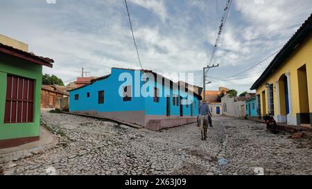 273 Reiter reiten neben einem Haus mit blauer Mauern auf rosa bemalten Sockel, Calle Amargura Street und Callejon de la Soledad Alley Ecke. Trinidad-Kuba. Stockfoto