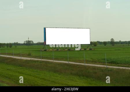 Ein hoch aufragendes Plakat am Straßenrand zieht mit seiner auffälligen Werbebotschaft die Aufmerksamkeit vorbeifahrender Fahrer auf sich. Stockfoto