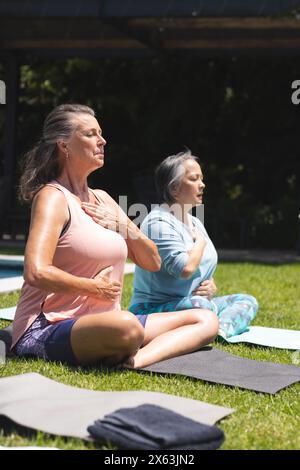 Verschiedene ältere Freundinnen üben Yoga im Freien Stockfoto