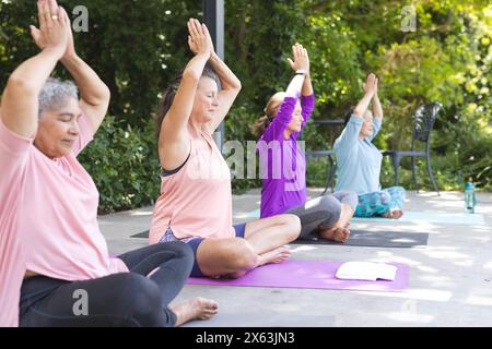 Verschiedene ältere Freundinnen üben Yoga im Freien und genießen grünen Hintergrund Stockfoto