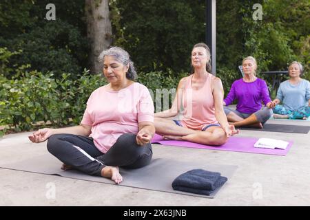 Verschiedene ältere Freundinnen üben Yoga im Freien Stockfoto