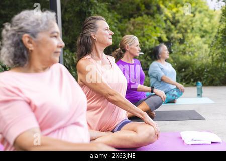 Verschiedene ältere Freundinnen üben Yoga im Freien Stockfoto