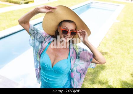 Draußen steht eine kaukasische Seniorin in Badeanzügen am Pool Stockfoto
