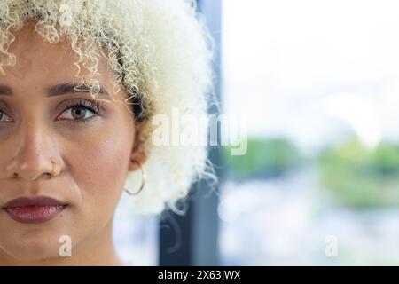 Im modernen Büro schreibt eine birassische Frau mit blonden Locken auf ihrem Laptop, Kopierraum Stockfoto