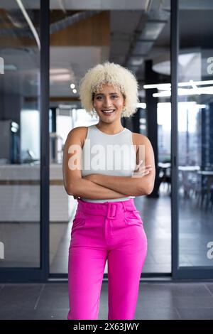 In einem modernen Büro steht eine junge Frau, die in die Kamera lächelt Stockfoto