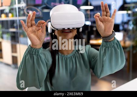 Im Büro arbeitet eine birassische Geschäftsfrau mit Virtual-Reality-Headset bis spät Stockfoto