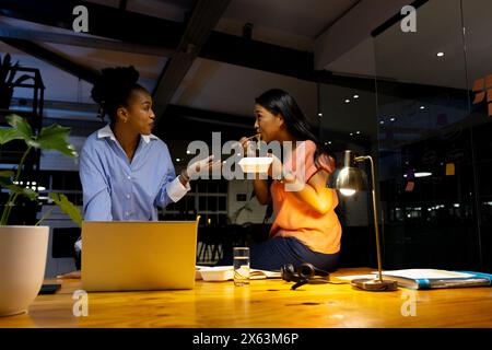 Verschiedene weibliche Kollegen diskutieren beim Abendessen, arbeiten bis spät Stockfoto