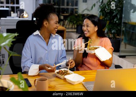 Verschiedene weibliche Kollegen genießen eine Mahlzeit und arbeiten spät im Büro Stockfoto