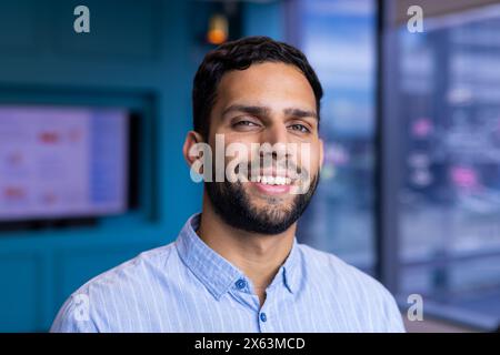 Ein junger birassischer Profi-Mann mit Bart, der im Büro vor die Kamera lächelt Stockfoto